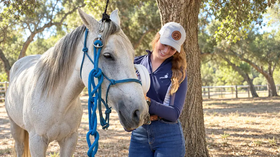 Sydnie smiling beside a grey therapy horse at Homefront Horsemanship