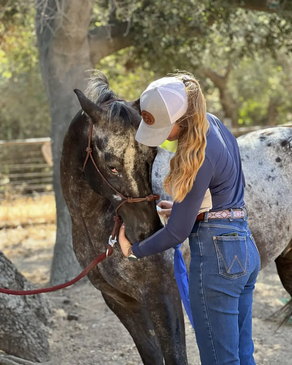 Sydnie hugging an Appaloosa therapy horse under an oak tree
