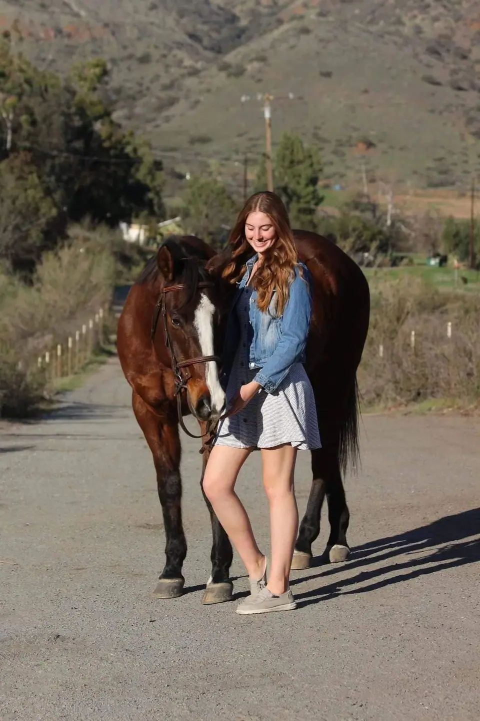 Sydnie standing with a bay horse on a quiet country road