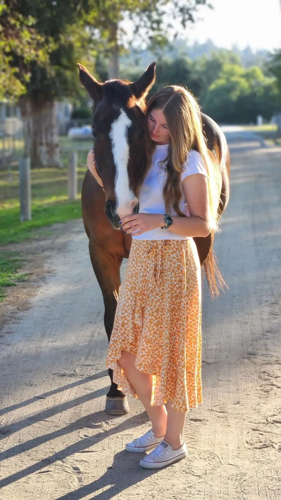 Sydnie resting her head against a chestnut horse with a white blaze
