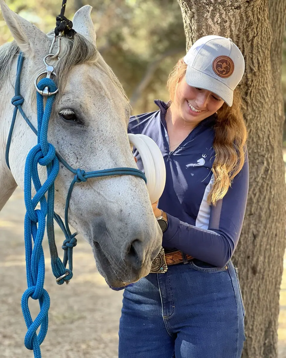 Sydnie smiling beside a grey therapy horse